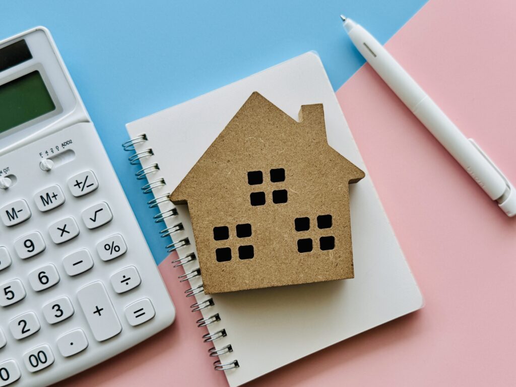 家の模型と電卓、ノート、ペン